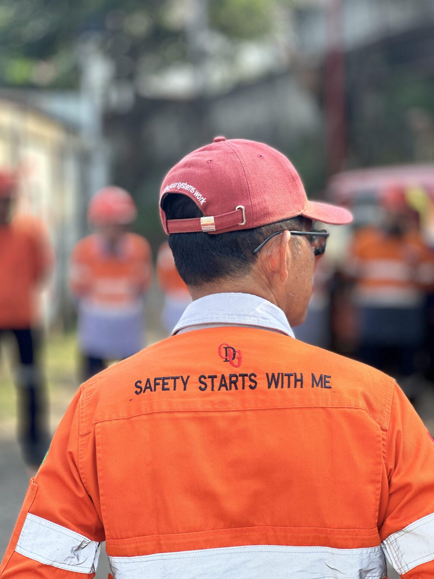 Safety Starts with me A man wearing an orange safety uniform that says Safety Starts with Me, ODG Indonesia tagline